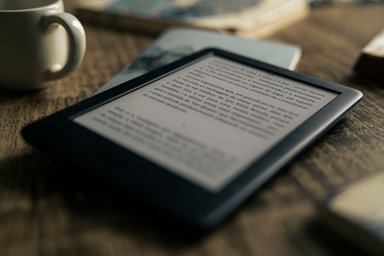 A tablet displaying an ebook on a wooden table next to a coffee cup, ideal for tech and lifestyle themes.